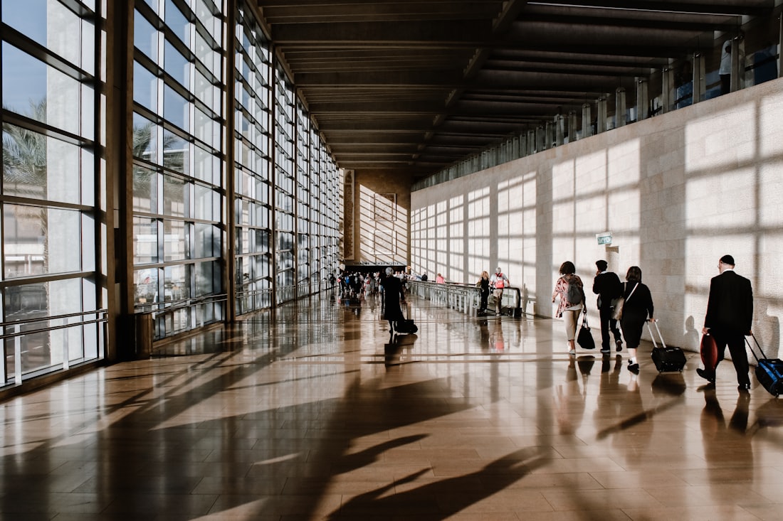 Un voyageur traverse le hall lumineux d'un aeroport, bagage a la main, avant son vol